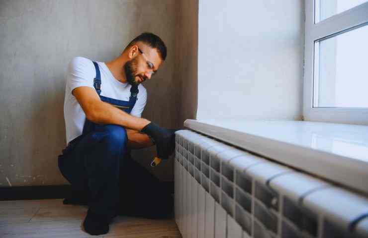 uomo ripara termosifone