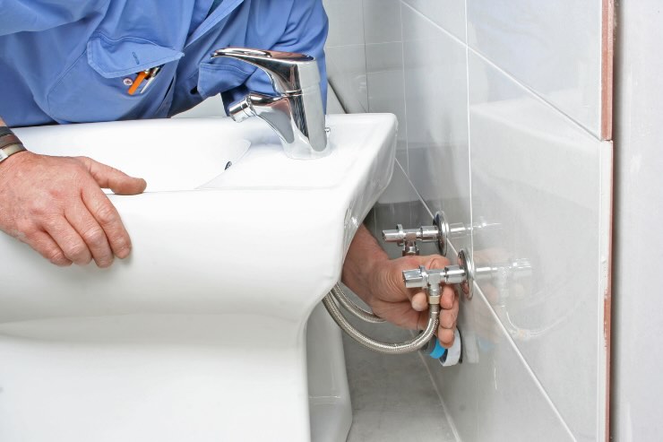 persona che sistema tubi dietro bidet