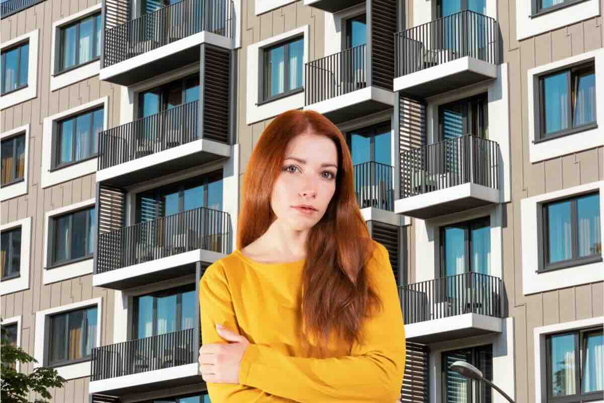 Donna braccia conserte, dietro di lei facciata palazzo