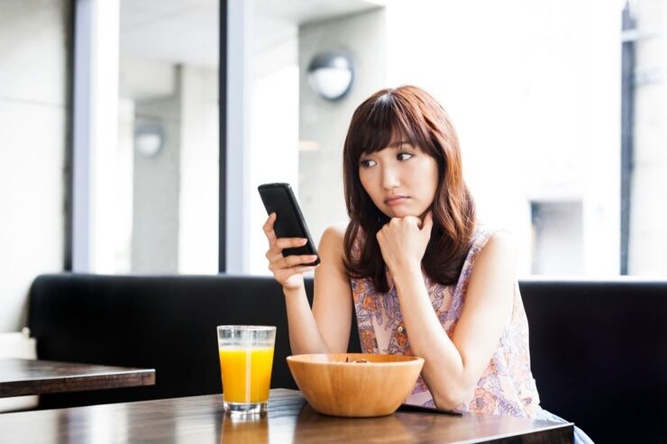Ragazza triste con smartphone al bar