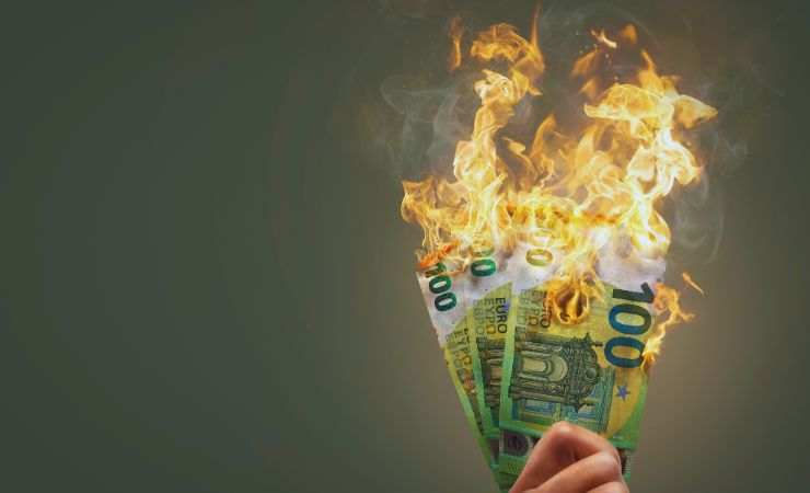 soldi in mano che prendono fuoco