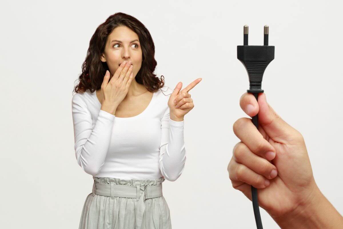 Donna che indica mano con spina corrente