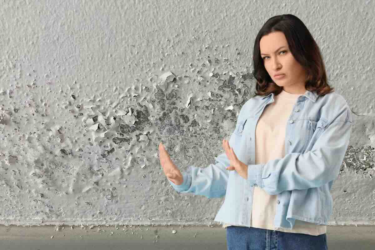Donna che fa stop a umidità sul muro
