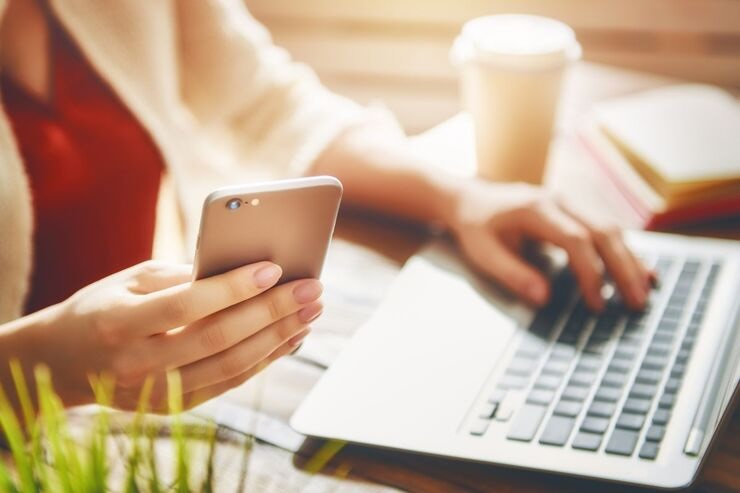 Mani una sul cellulare e una sulla tastiera del PC