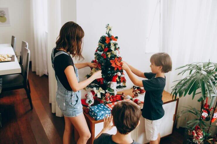 3 bambini addobbano albero di Natale