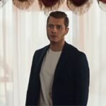 Cihan protagonista la notte nel cuore, ragazzo con giacca nera maglia bianca davanti alla finestra con tende bianche