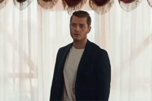 Cihan protagonista la notte nel cuore, ragazzo con giacca nera maglia bianca davanti alla finestra con tende bianche