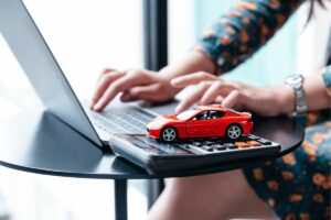 mani che digitano su pc e macchinina rossa