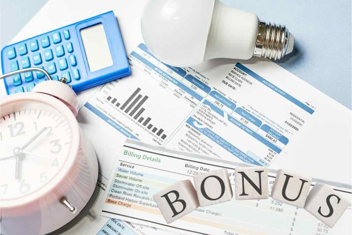 Documenti con bollette, sveglia, calcolatrice, lampadina, scritta "bonus"