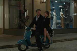 Marcello e Adelaide in sella ad una moto davanti la vetrina del Paradiso