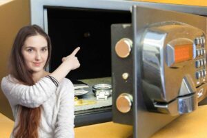 Donna indica interno di cassaforte con orologio e portafoglio