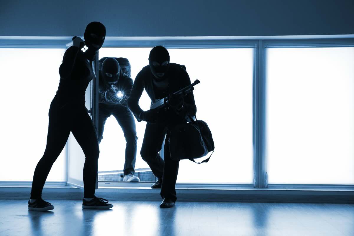 tre uomini vestiti di nero che entrano in casa con torce