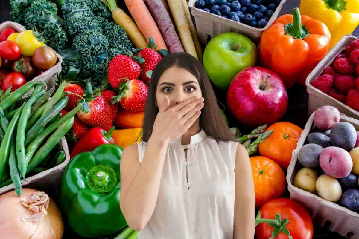 Donna con mano sulla bocca, frutta e verdura dietro di lei